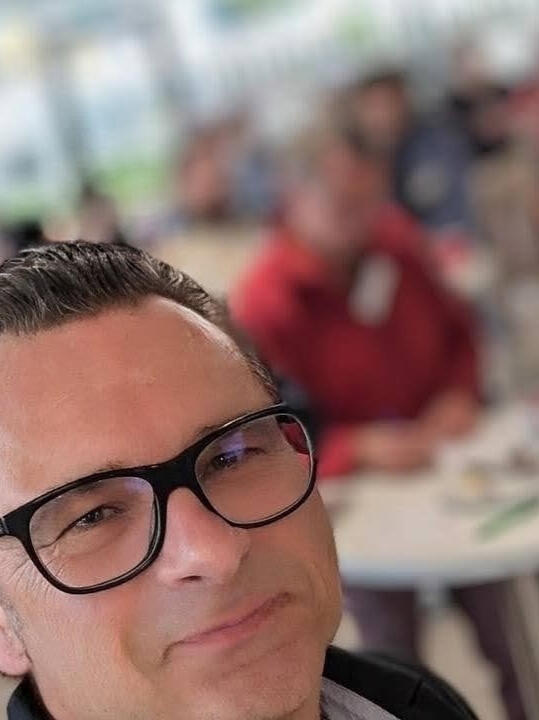 Josef Rossmann bei einer Veranstaltung mit Publikum im Hintergrund